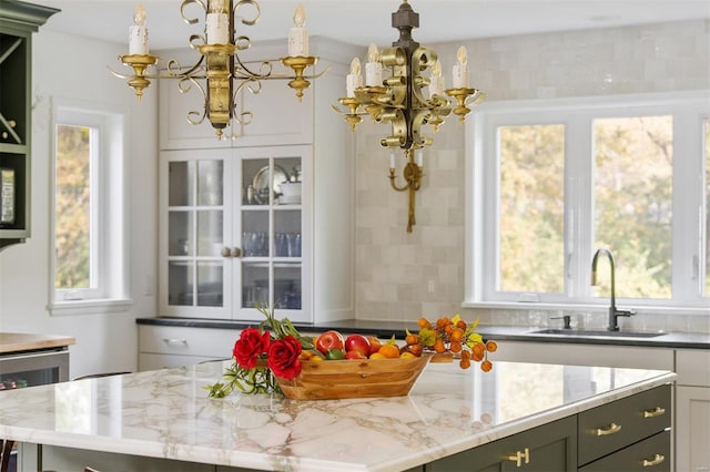 kitchen with light stone countertops, a wealth of natural light, sink, and beverage cooler