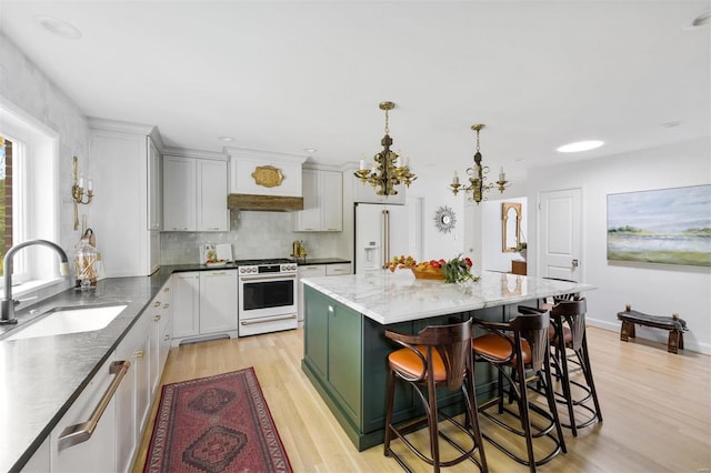 kitchen with white cabinets, a center island, white appliances, and sink