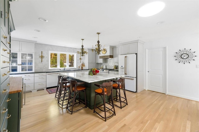 kitchen with light hardwood / wood-style flooring, a kitchen island, hanging light fixtures, and white appliances