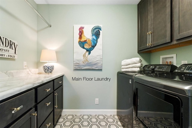 laundry area featuring separate washer and dryer, light tile patterned floors, and cabinets