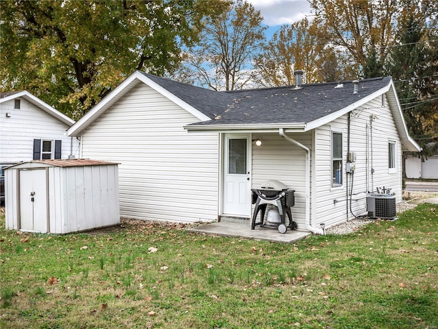 back of property with central AC, a patio area, a lawn, and a shed