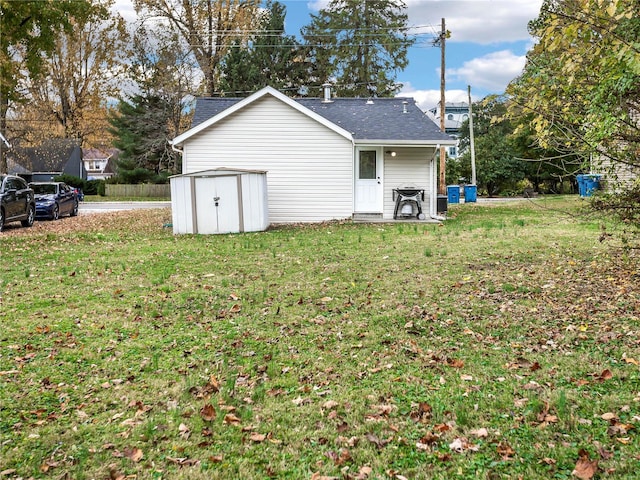 rear view of house featuring a lawn and a storage unit