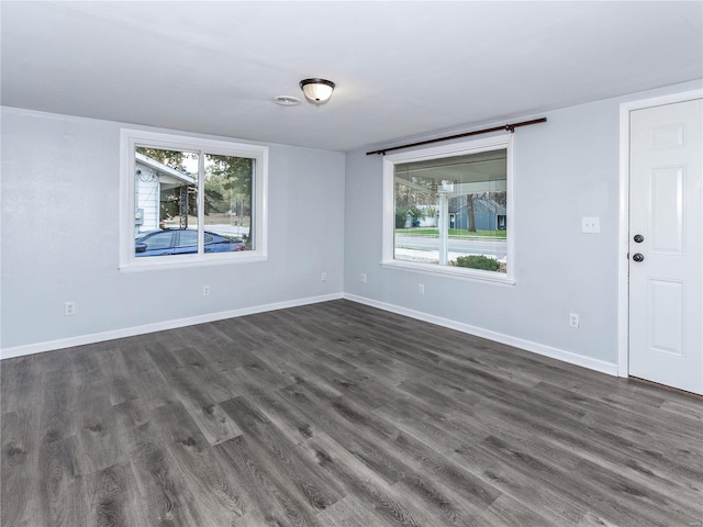 spare room with dark hardwood / wood-style flooring and a healthy amount of sunlight