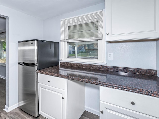 kitchen with dark hardwood / wood-style flooring, white cabinetry, dark stone countertops, and stainless steel fridge