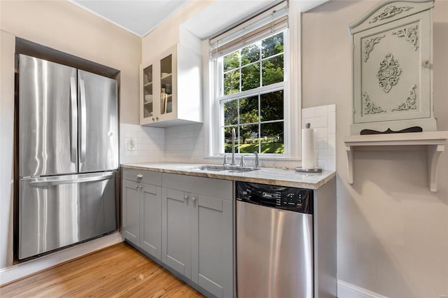 kitchen featuring light hardwood / wood-style flooring, gray cabinets, light stone countertops, tasteful backsplash, and stainless steel appliances