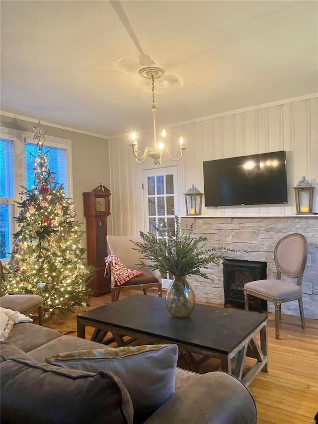 living room with a notable chandelier, a fireplace, crown molding, and light hardwood / wood-style flooring