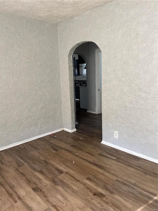 empty room with dark hardwood / wood-style floors, a textured ceiling, and sink