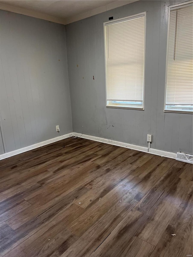 unfurnished room with wood walls and dark wood-type flooring