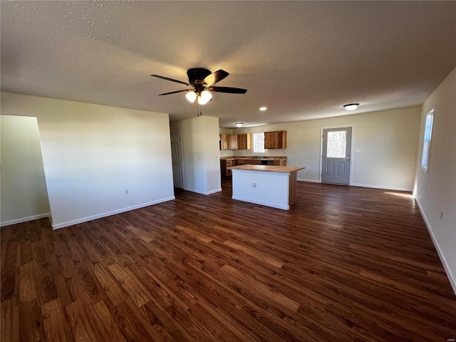 unfurnished living room with ceiling fan, dark wood-type flooring, and a textured ceiling