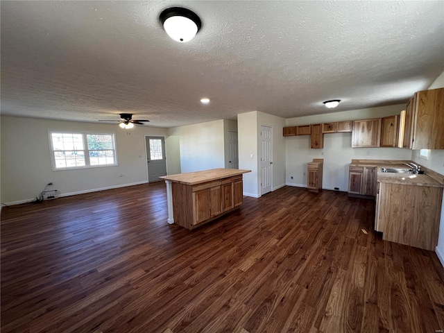 kitchen featuring ceiling fan, a center island, dark wood-type flooring, and a textured ceiling