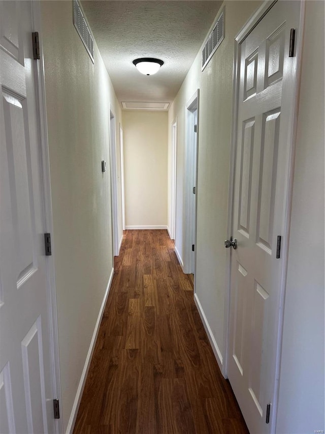 hallway with a textured ceiling and dark wood-type flooring