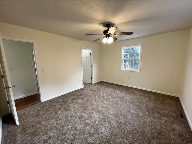 unfurnished bedroom featuring ceiling fan, dark carpet, and a textured ceiling