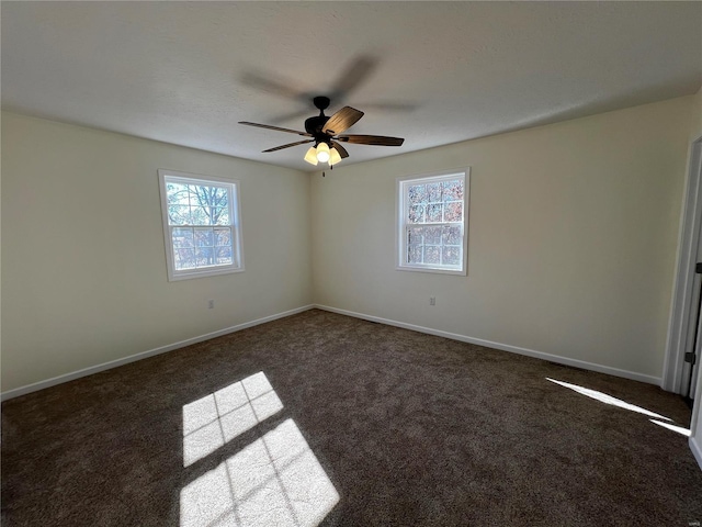 spare room featuring dark colored carpet and ceiling fan