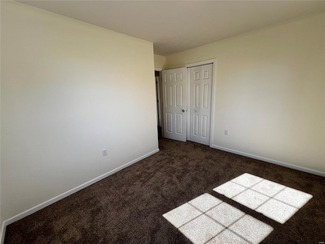 unfurnished bedroom with dark colored carpet and a closet