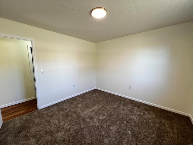 unfurnished room featuring dark carpet