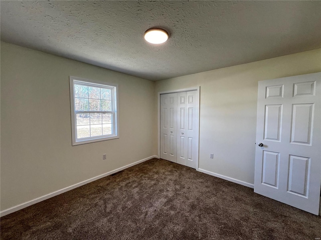 unfurnished bedroom featuring a closet, a textured ceiling, and dark colored carpet