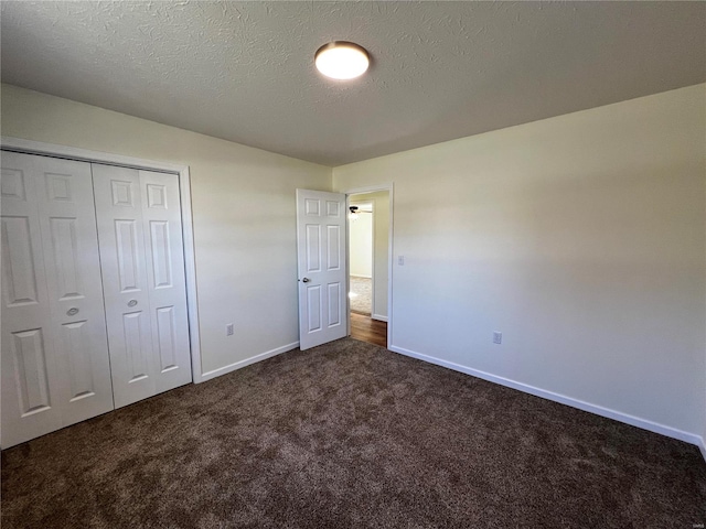 unfurnished bedroom with dark colored carpet, a textured ceiling, and a closet