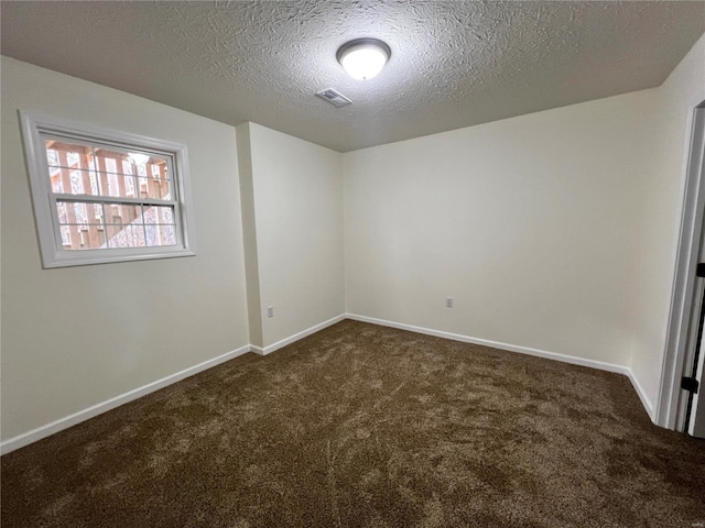 spare room featuring dark carpet and a textured ceiling