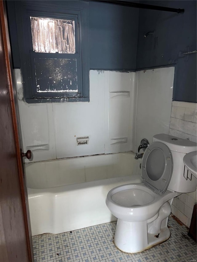 bathroom with toilet, tub / shower combination, tile walls, and tile patterned floors