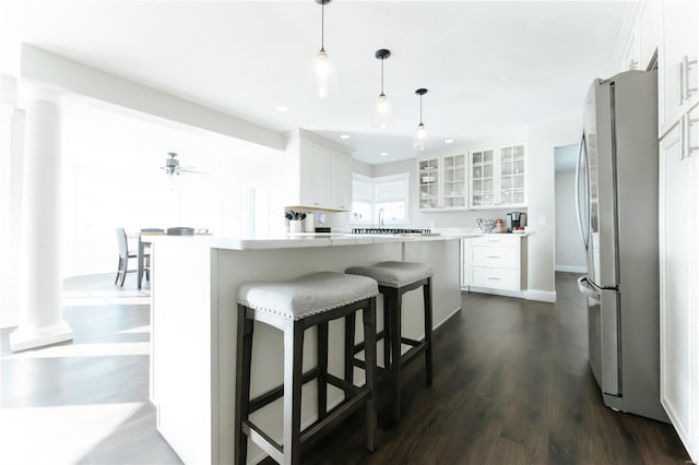 kitchen featuring pendant lighting, dark wood-type flooring, a kitchen island, white cabinetry, and stainless steel refrigerator