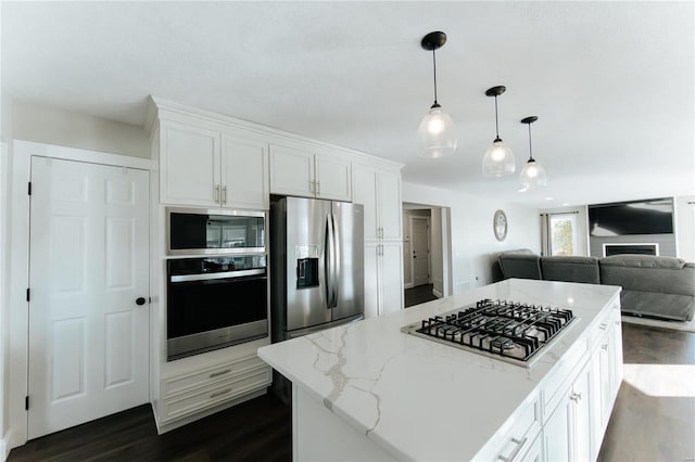 kitchen featuring dark wood-type flooring, hanging light fixtures, appliances with stainless steel finishes, light stone counters, and white cabinetry