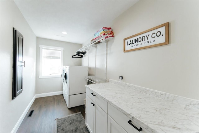 washroom with washer and dryer, cabinets, and dark wood-type flooring