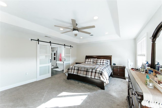 bedroom with ceiling fan, a barn door, a raised ceiling, and light carpet