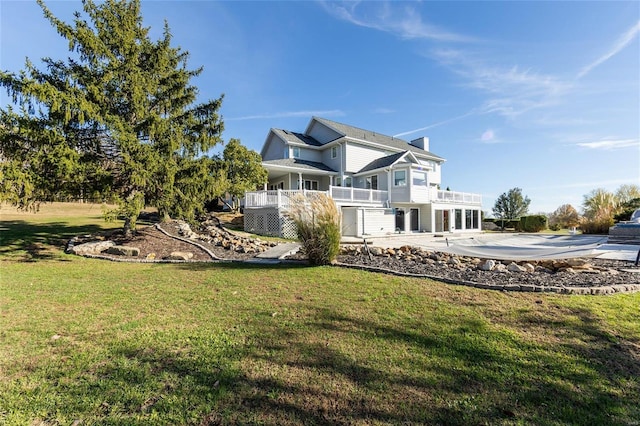 back of property with a lawn, a balcony, and a patio