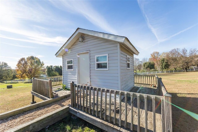 back of house featuring a lawn, an outdoor structure, and a wooden deck