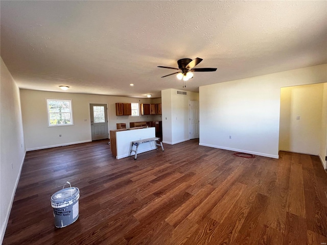 unfurnished living room featuring a textured ceiling, ceiling fan, and dark wood-type flooring