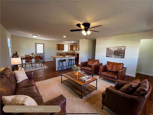 living room with a textured ceiling, light hardwood / wood-style floors, and ceiling fan