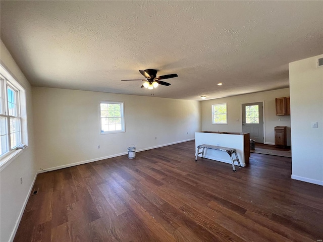 interior space featuring a textured ceiling, dark hardwood / wood-style floors, ceiling fan, and a healthy amount of sunlight