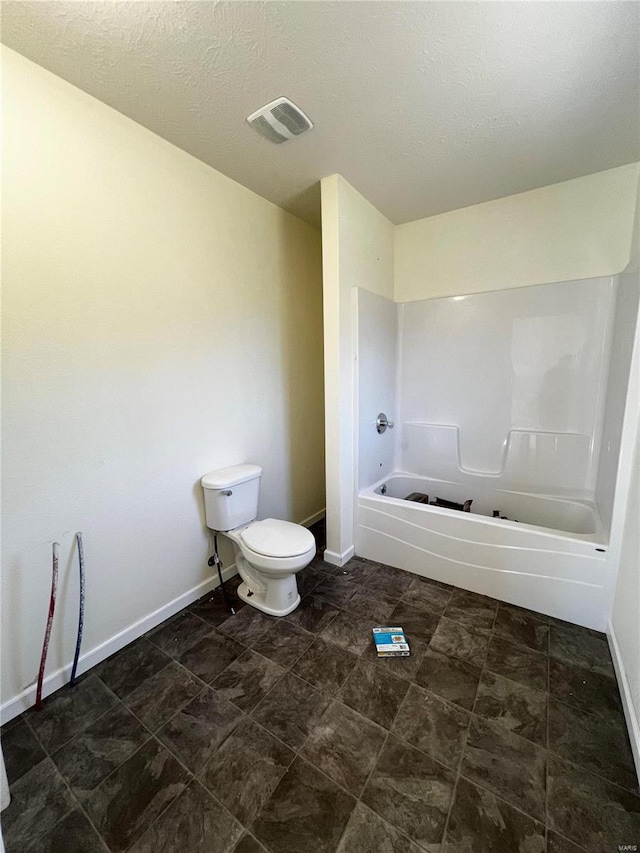 bathroom with toilet, a textured ceiling, and bathtub / shower combination