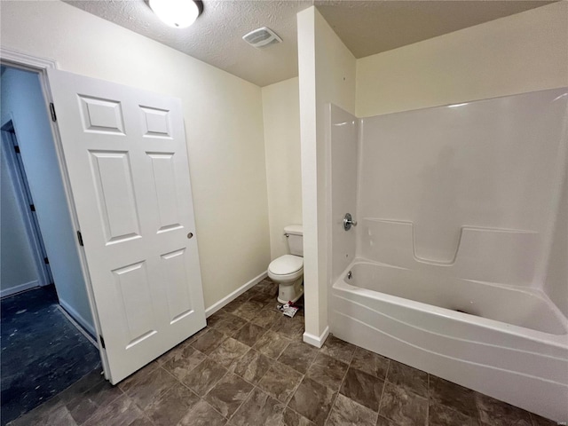 bathroom featuring washtub / shower combination, a textured ceiling, and toilet