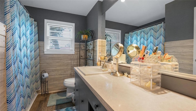 bathroom with wooden walls, toilet, a healthy amount of sunlight, and hardwood / wood-style flooring