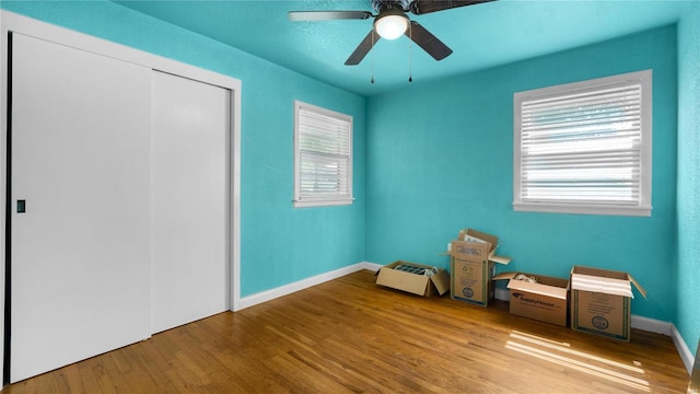 unfurnished bedroom with ceiling fan, a closet, and wood-type flooring