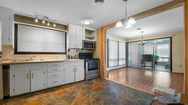 kitchen featuring appliances with stainless steel finishes, sink, dark hardwood / wood-style floors, white cabinetry, and hanging light fixtures