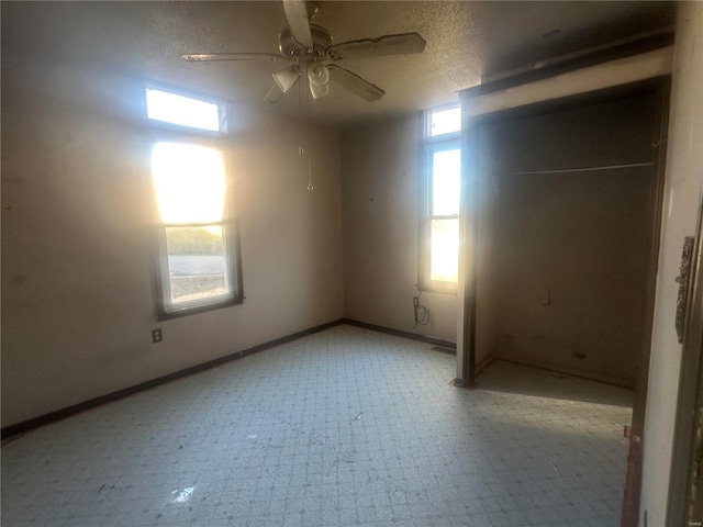 unfurnished room with ceiling fan, a healthy amount of sunlight, and a textured ceiling