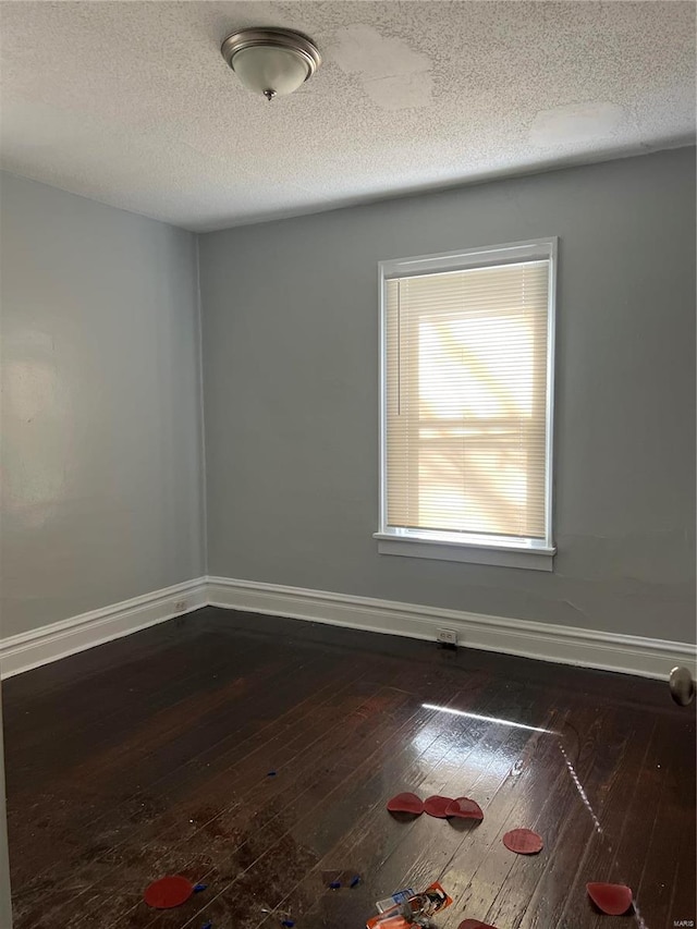 unfurnished room with dark wood-type flooring and a textured ceiling