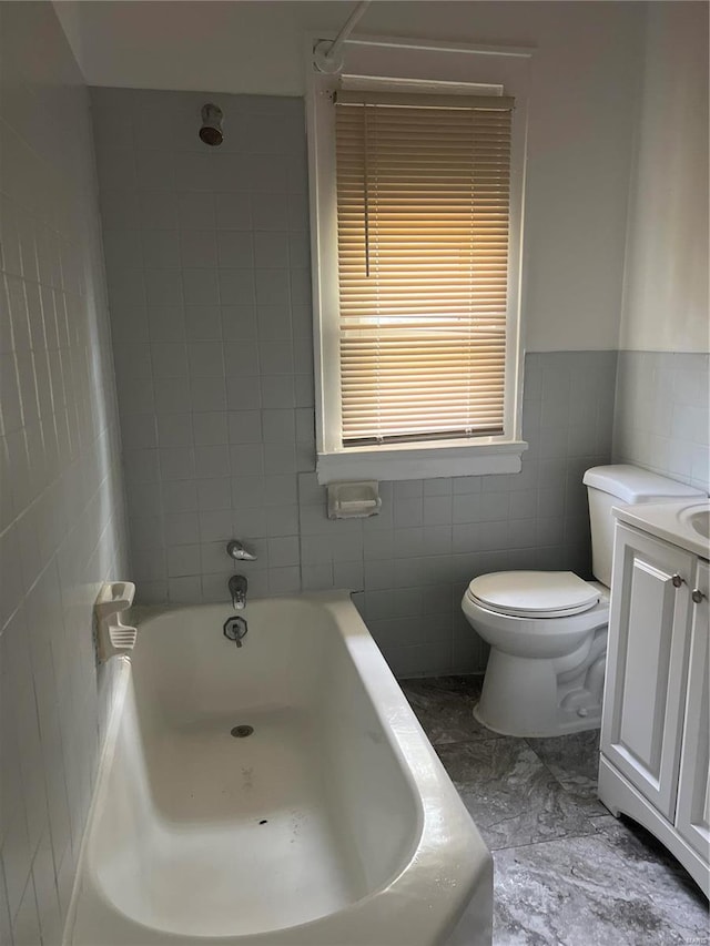 full bathroom featuring vanity, toilet, tiled shower / bath, and tile walls