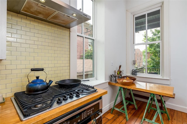 kitchen with hardwood / wood-style flooring, stainless steel gas cooktop, wooden counters, range hood, and decorative backsplash