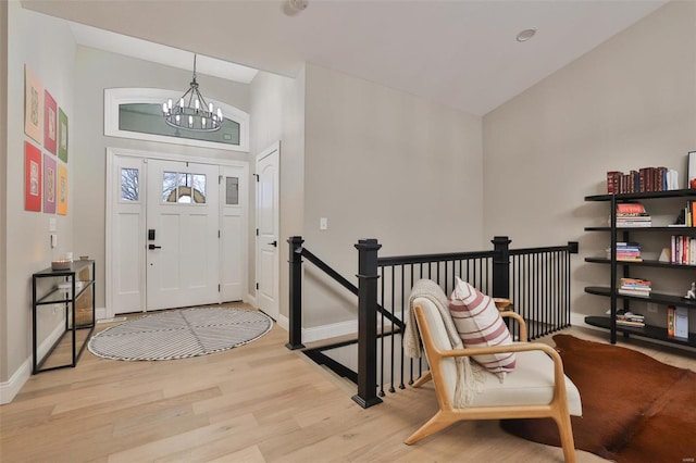 entryway featuring vaulted ceiling, light wood-type flooring, and an inviting chandelier