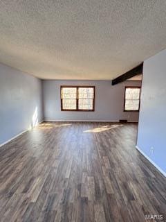 spare room featuring beamed ceiling, dark wood-type flooring, and a textured ceiling