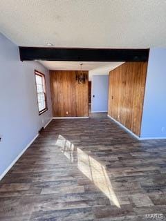 unfurnished living room with a textured ceiling, dark hardwood / wood-style flooring, and wooden walls