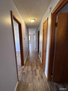 hallway featuring dark wood-type flooring and a textured ceiling