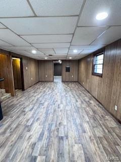 basement with wood walls, a paneled ceiling, and hardwood / wood-style floors