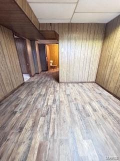 interior space featuring a paneled ceiling, wood walls, and hardwood / wood-style flooring