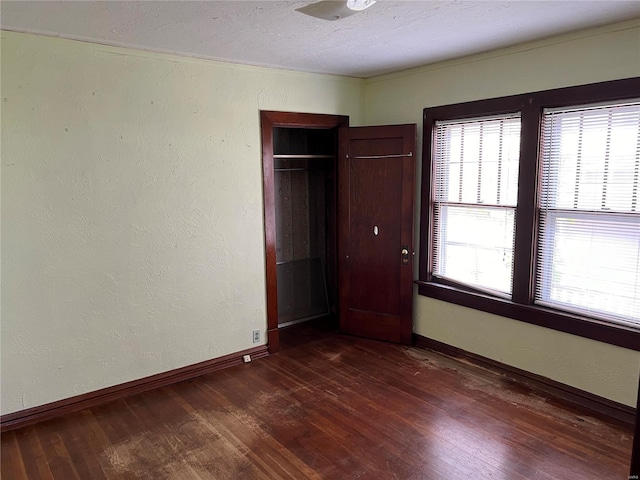 unfurnished bedroom featuring dark wood-type flooring, a closet, and crown molding