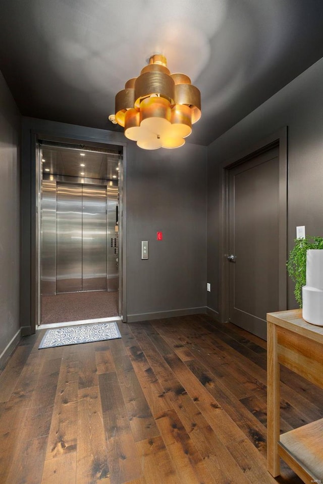 interior space with elevator, dark hardwood / wood-style flooring, and an inviting chandelier