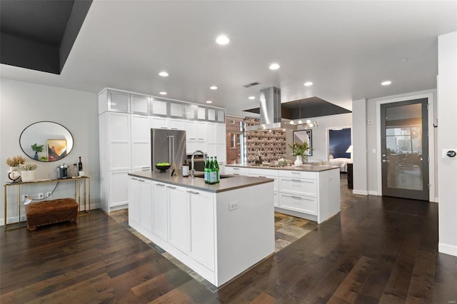 kitchen featuring island exhaust hood, an island with sink, dark hardwood / wood-style floors, and appliances with stainless steel finishes